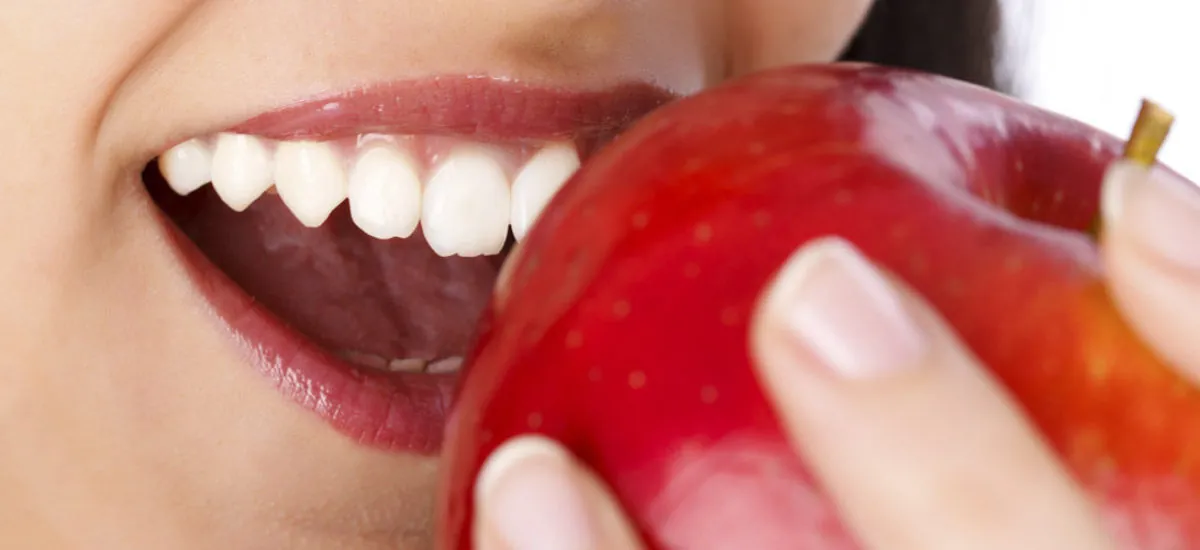 Sonrisa saludable mordiendo una manzana — filosofía de la Clínica Dental Mendizábal en Logroño, La Rioja